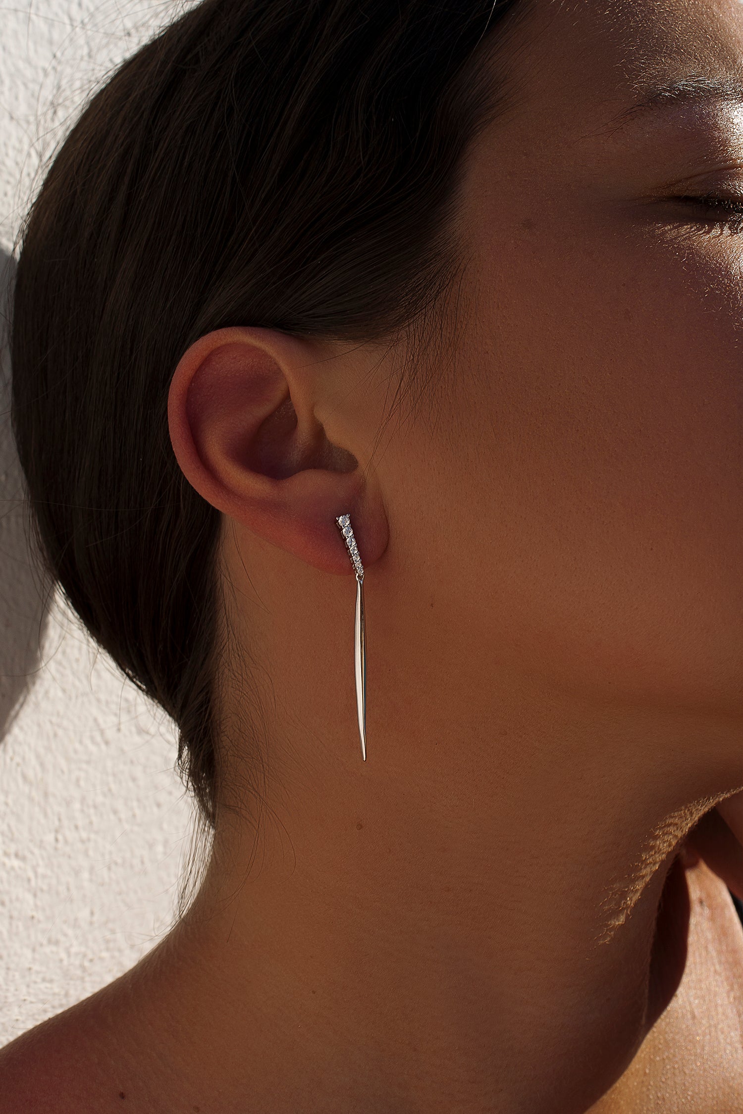 Long, static silver earrings with a strip of cubic zirconia and a pointed bar.