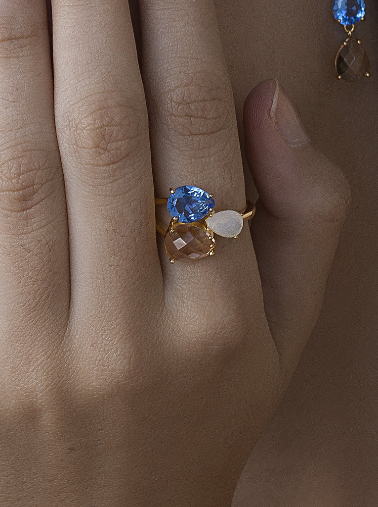 Anillo de plata acabado dorado con triple piedra azul blanco y champagne