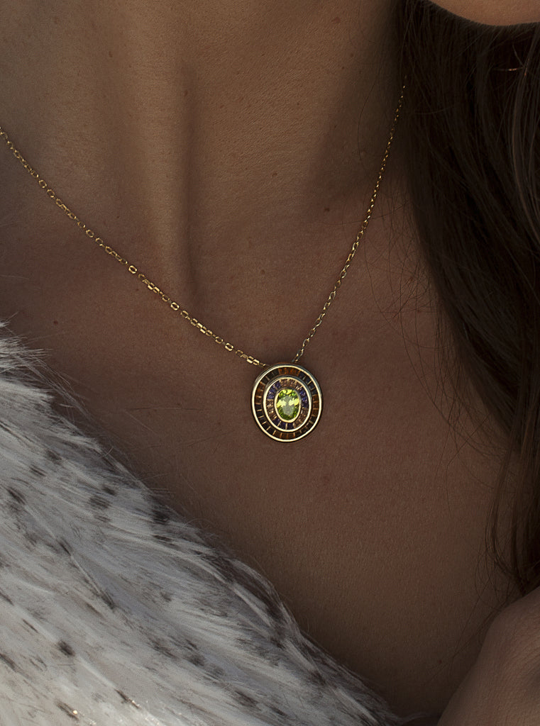 Collar con colgante halo circular y circonitas verdes con toques cálidos. plata bañada en oro para iluminar cualquier outfit.