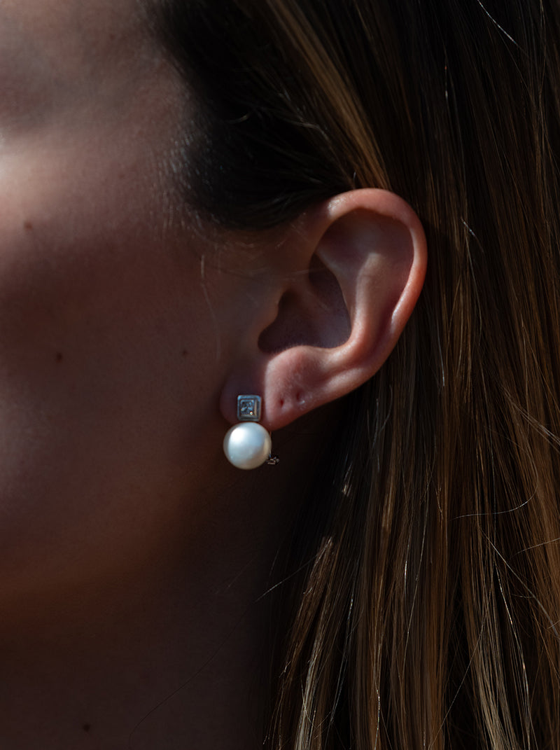 Silver pearl earrings in a toe-and-me style with a square cubic zirconia detail
