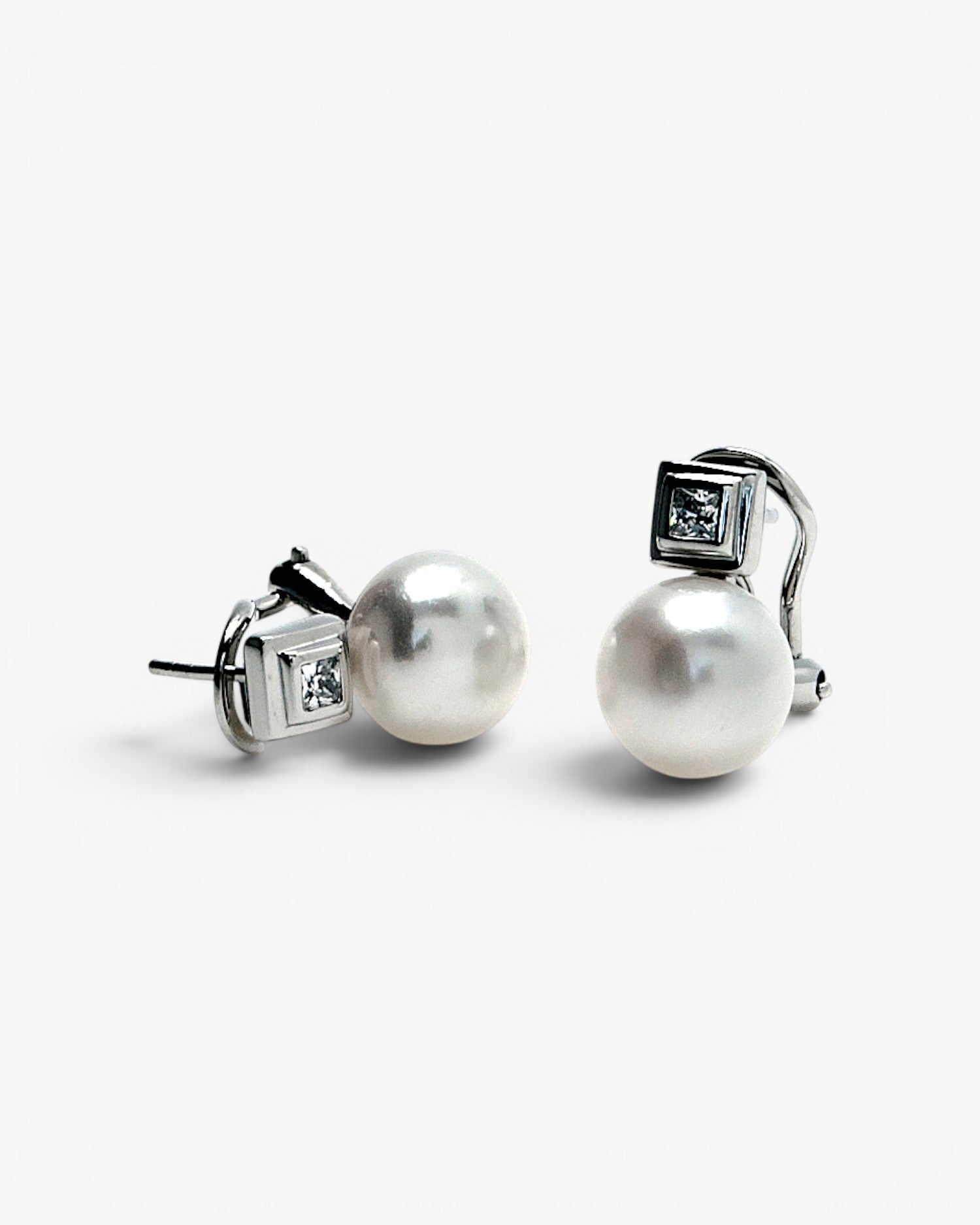 Silver pearl earrings in a toe-and-me style with a square cubic zirconia detail