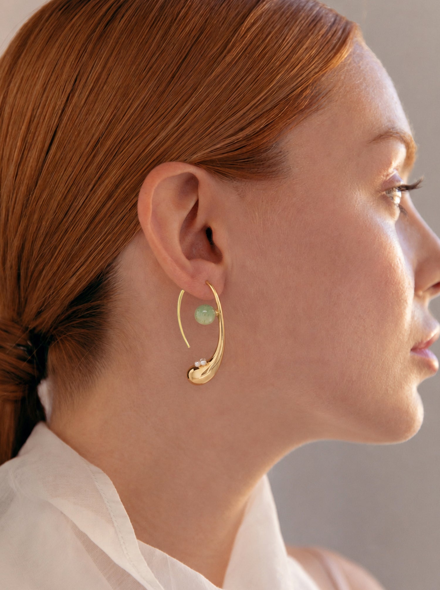 Pendientes curvos dorados con perlas y piedra verde