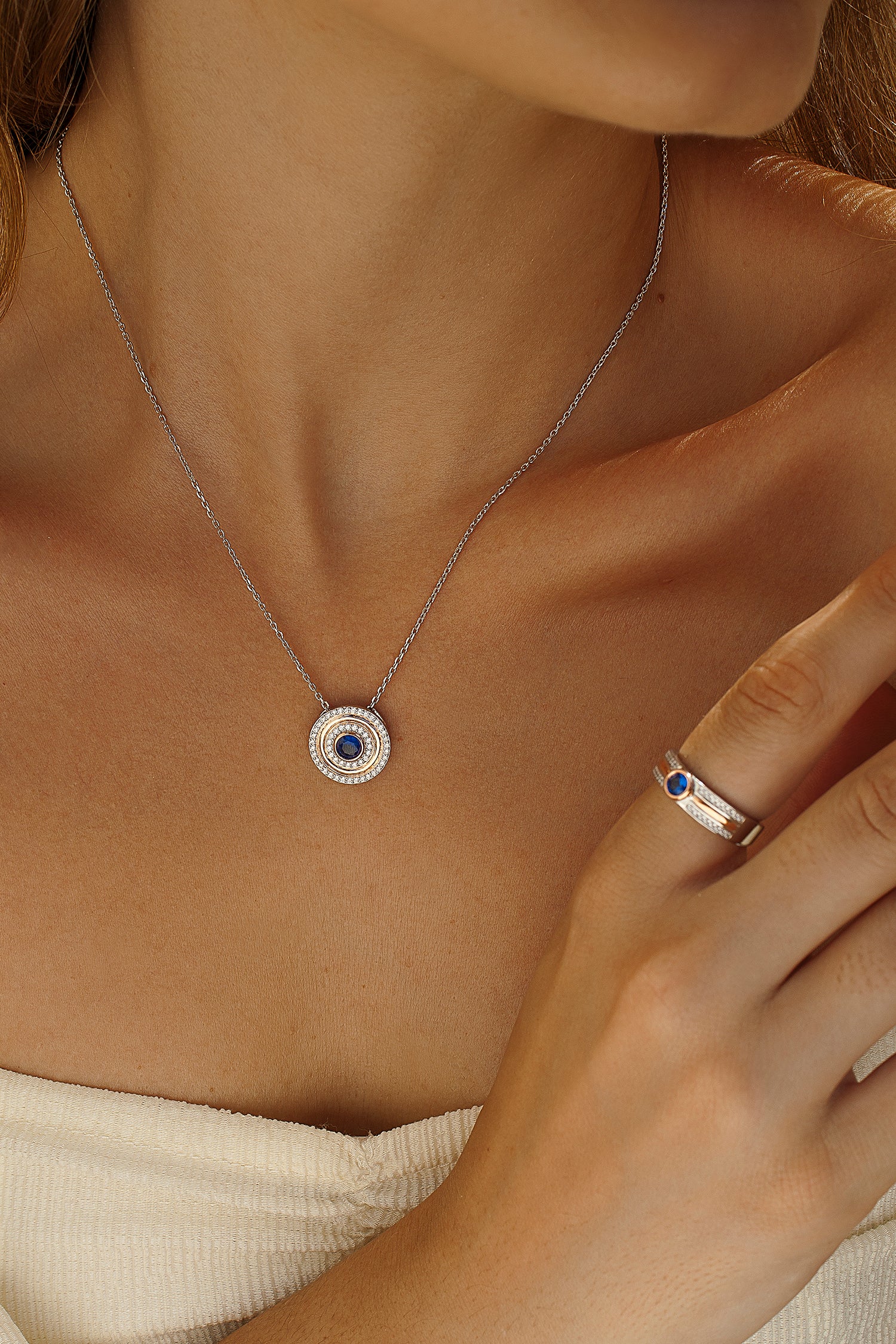 Collier médaillon orné de zirconiums cubiques et d'une pierre précieuse bleue centrale