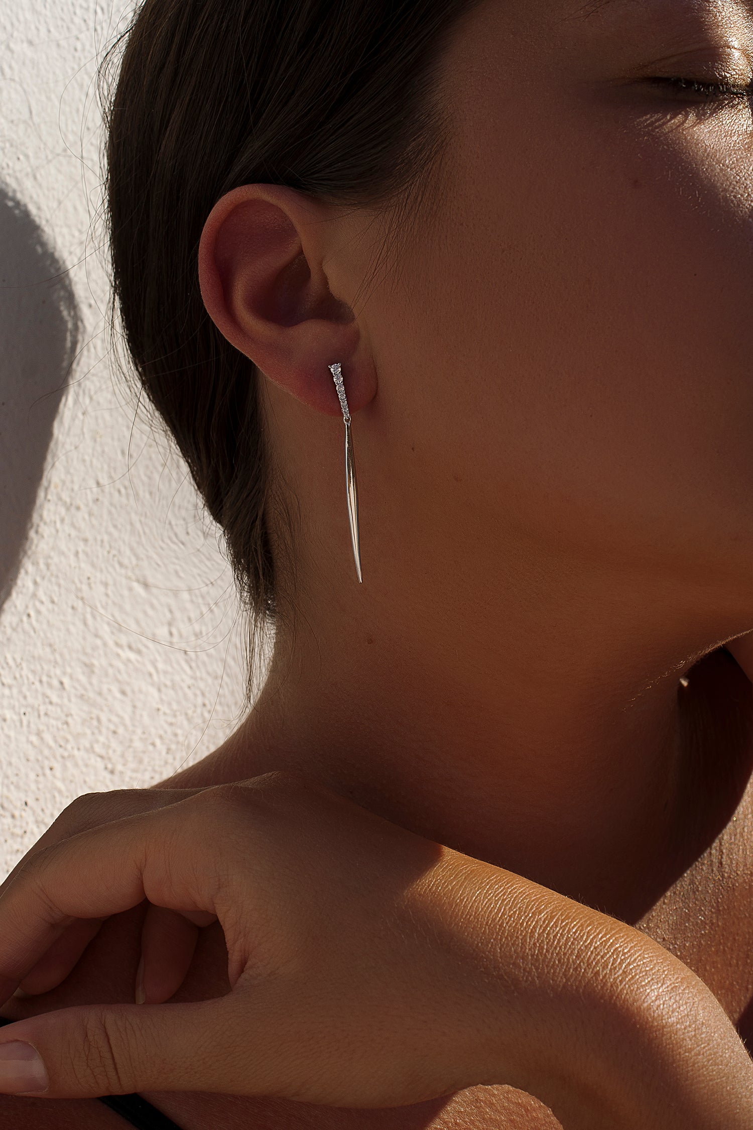 Long, static silver earrings with a strip of cubic zirconia and a pointed bar.
