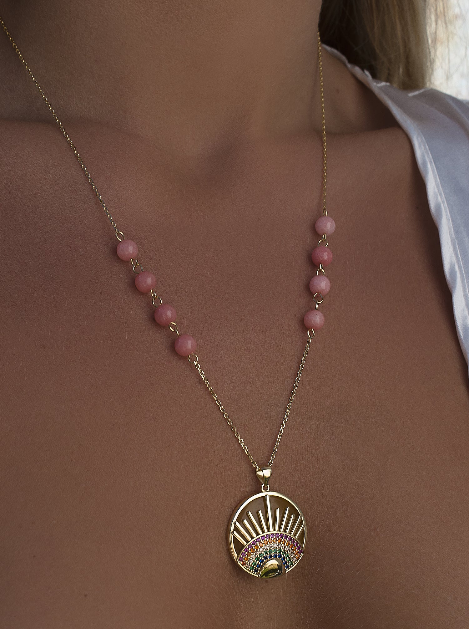 Collier orné d'un médaillon représentant un demi-arc-en-ciel et des rayons de soleil.