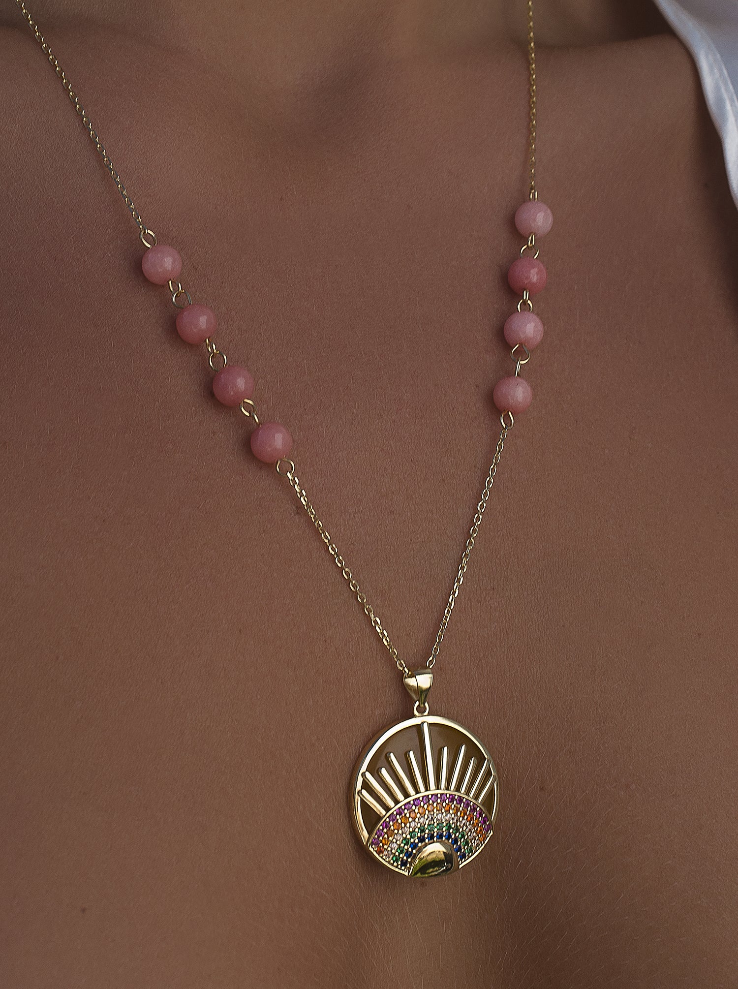 Collier orné d'un médaillon représentant un demi-arc-en-ciel et des rayons de soleil.