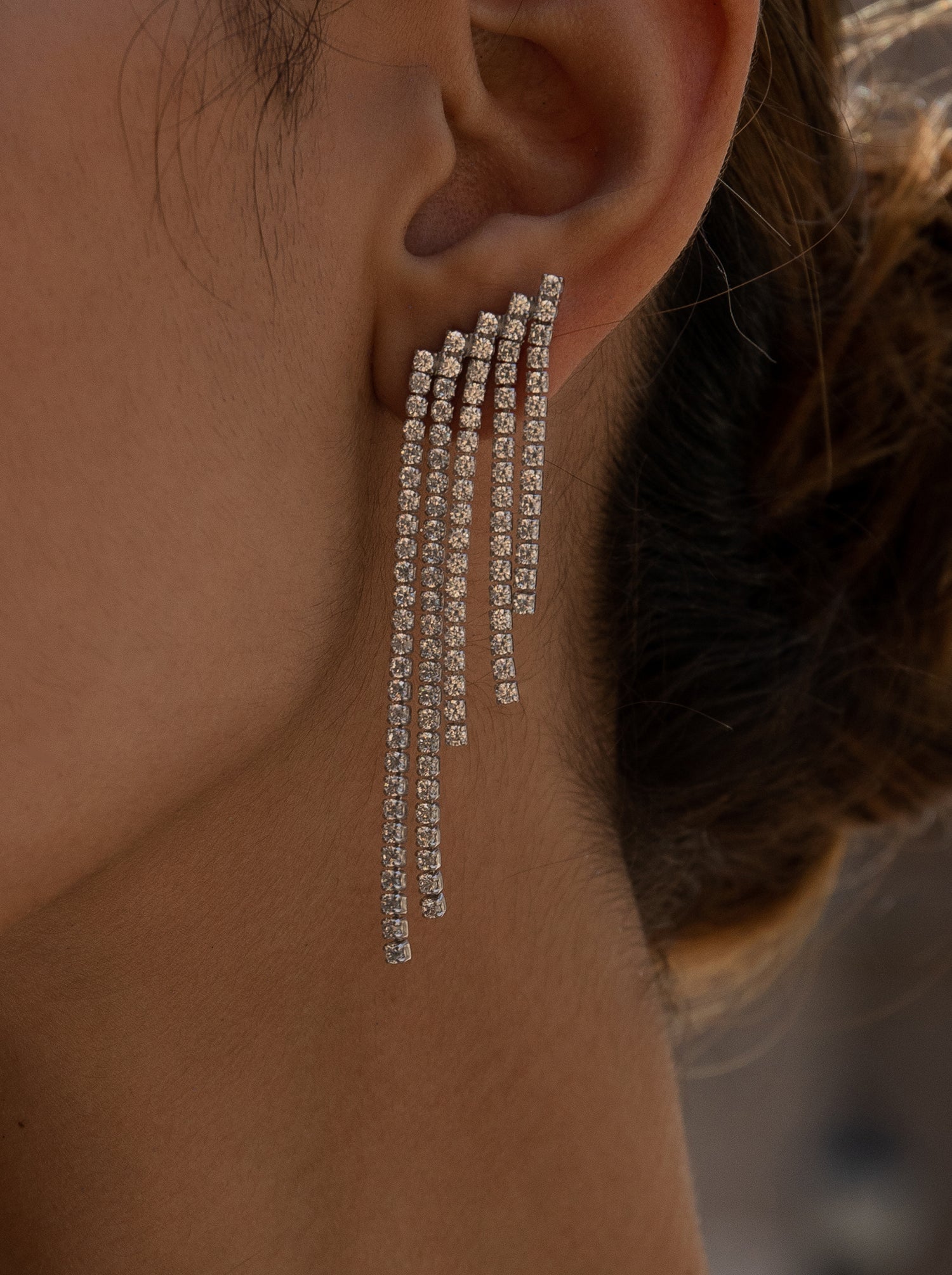 Long silver earrings with a design of four unequal strands of cubic zirconia