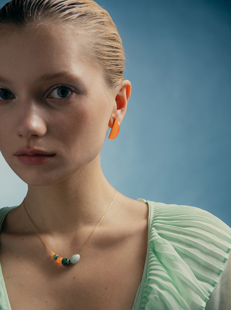 Boucles d'oreilles en pierre aux tons orangés, en forme de demi-cercle.