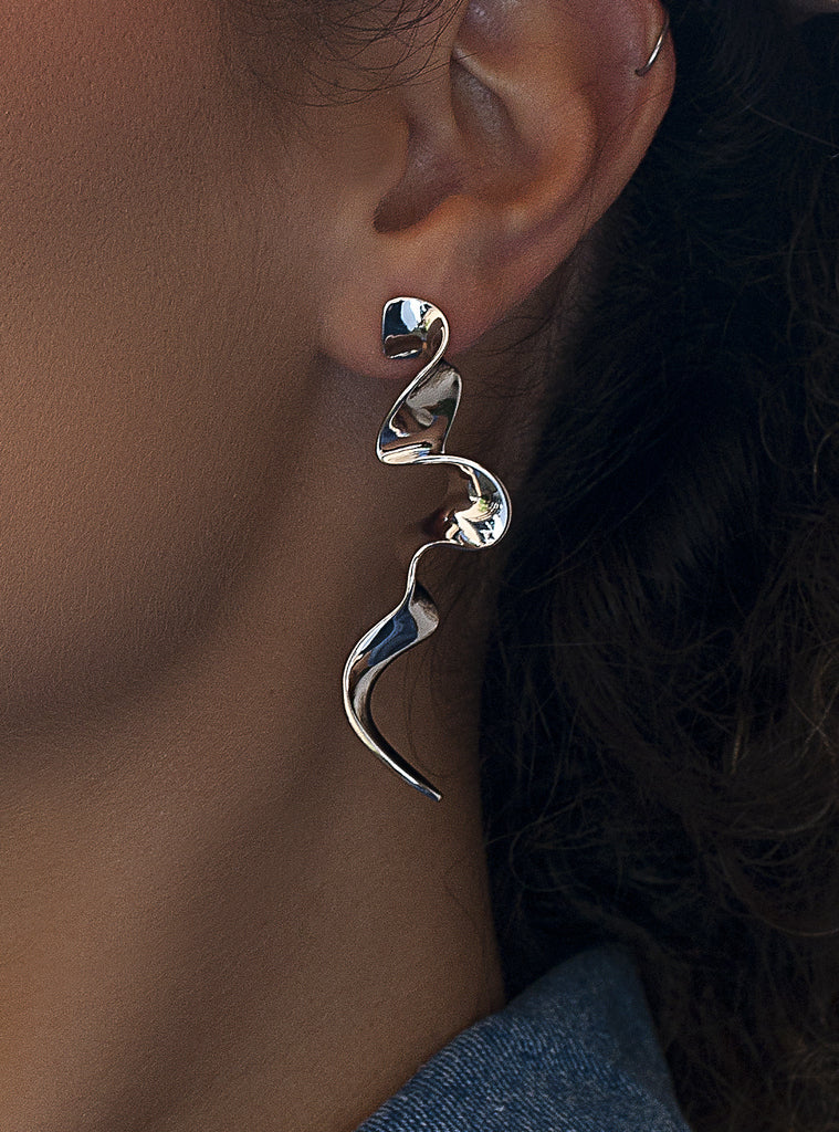Pendientes largos plateados de diseño ondulado y escultural
