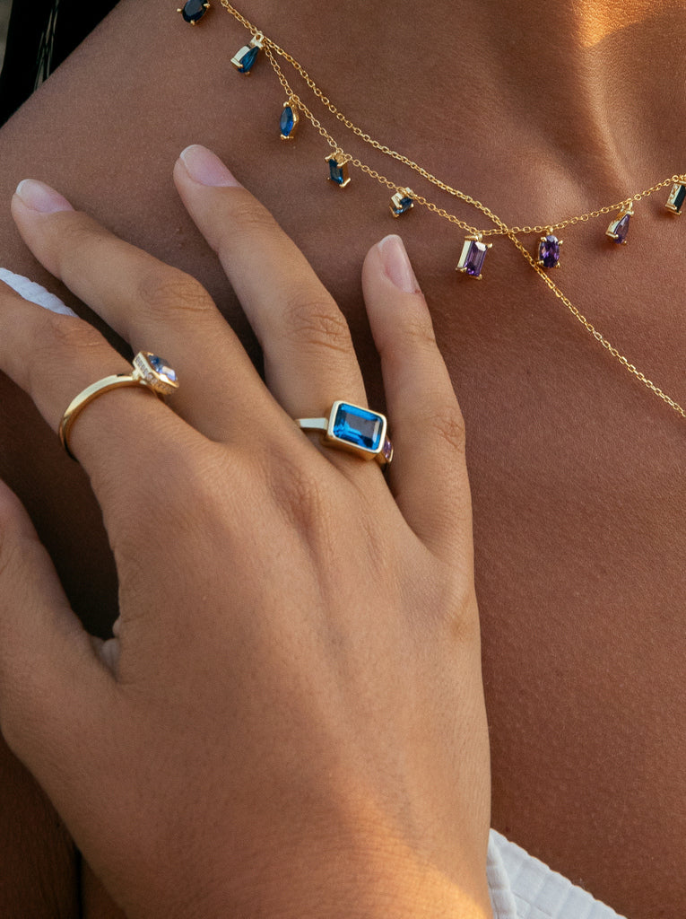 Anillo de plata de ley dorada con piedra rectangular azul y detalles lila
