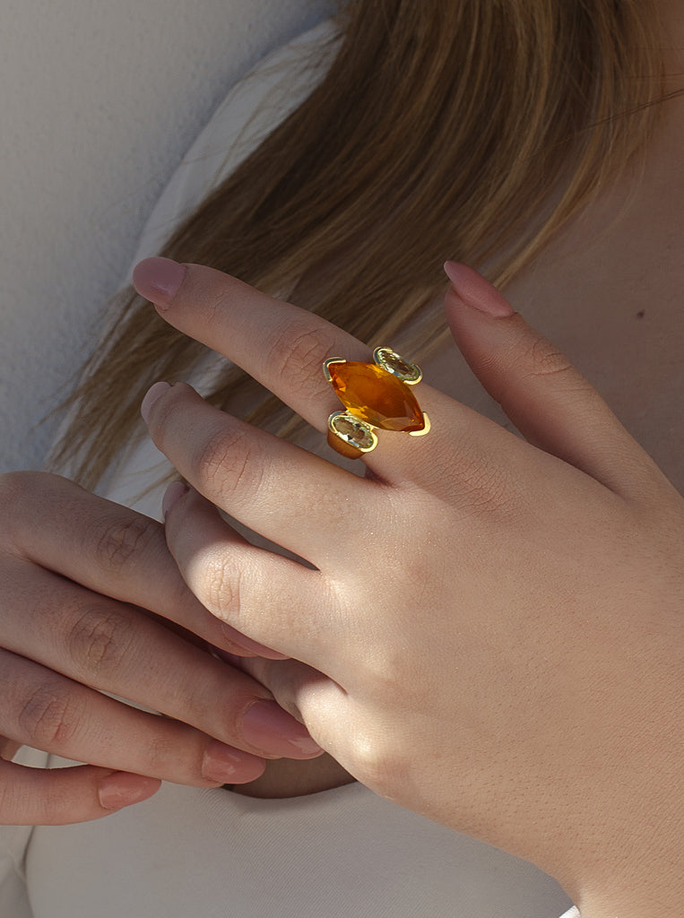 Anillo de plata bañado en oro con piedra naranja ámbar y detalles verdes