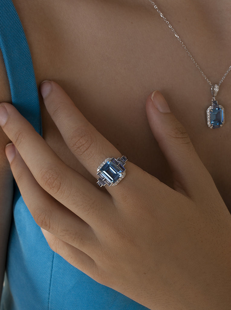 Anillo de plata con piedra azul rectangular y detalles lila