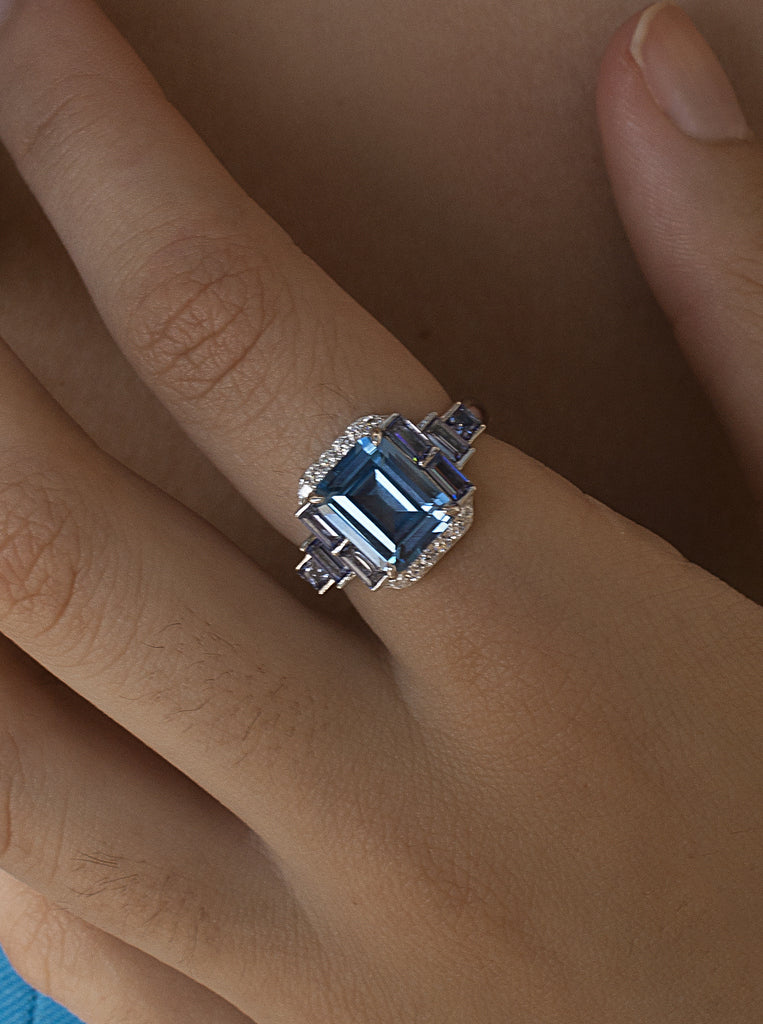 Anillo de plata con piedra azul rectangular y detalles lila