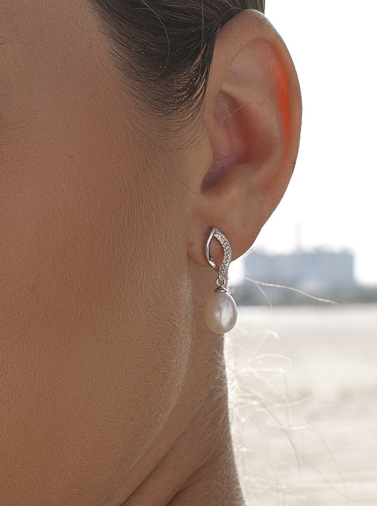 Silver earrings with a dangling pearl and interlocking design