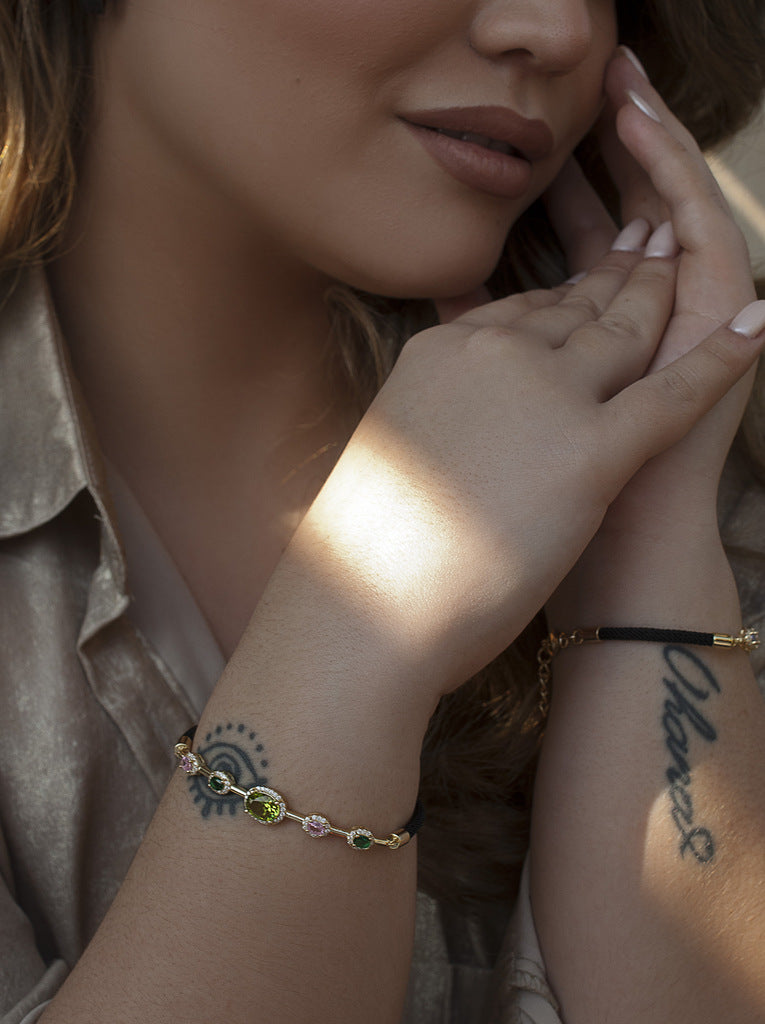 Pulsera de plata con piedras de colores en tonos verdes y cordón negro